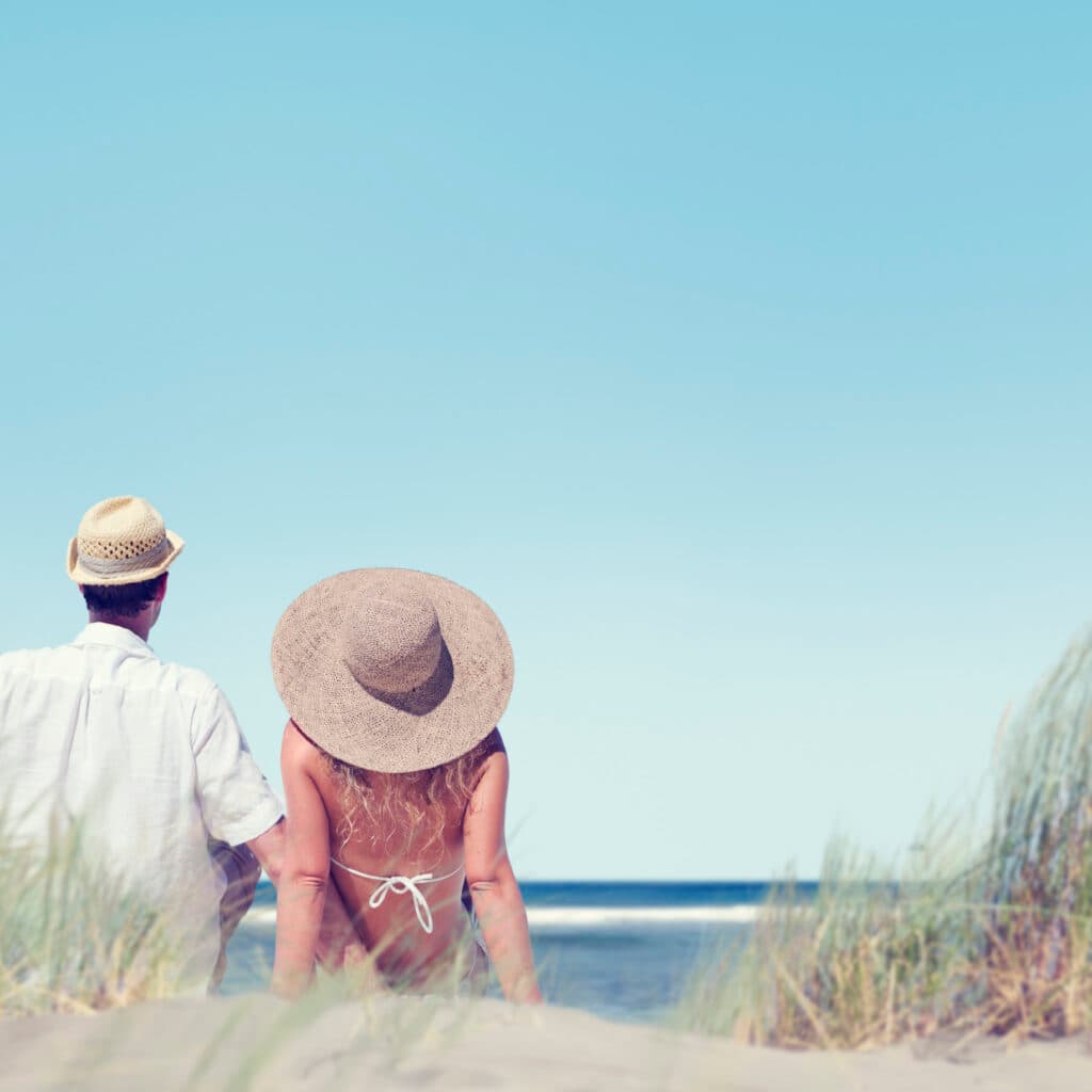 Kvinna och man sitter på en strand