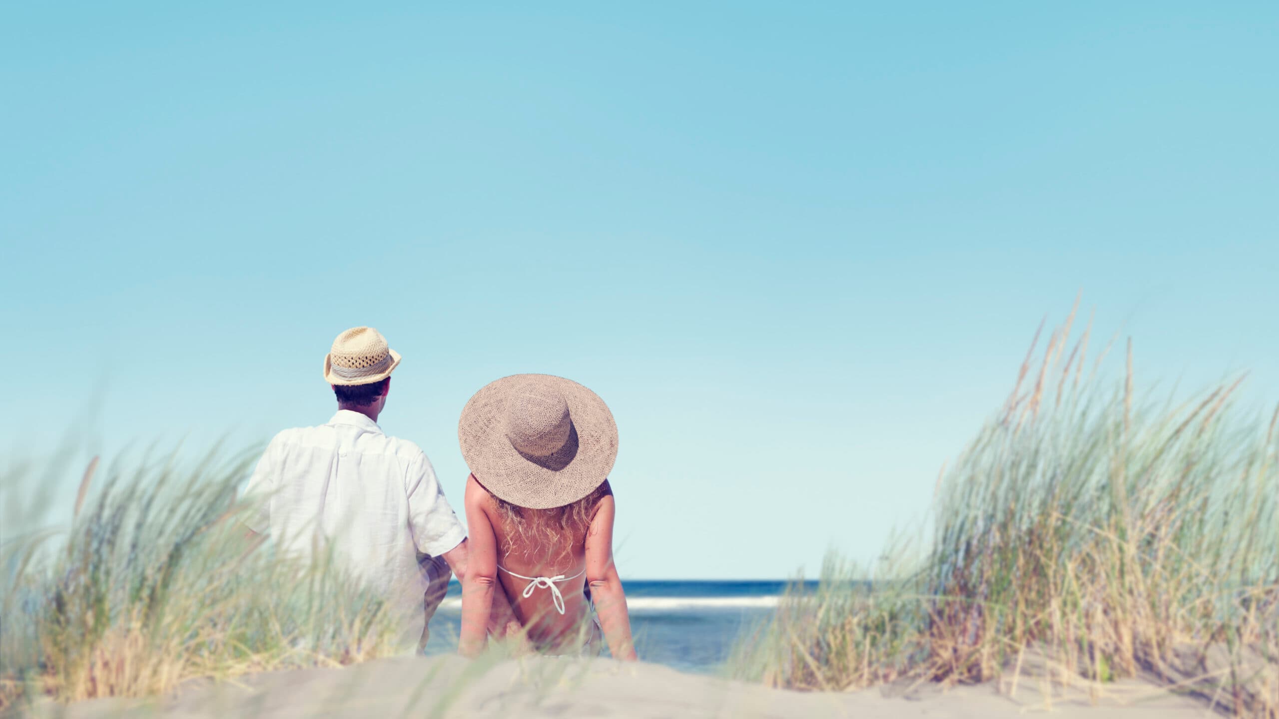 Kvinna och man sitter på en strand